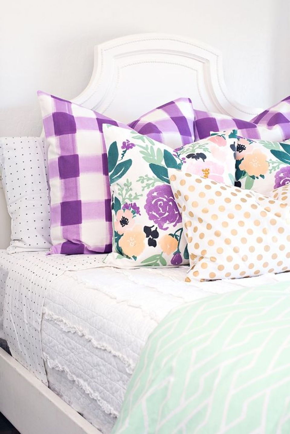 Cottage bedroom with purple gingham and floral patterned pillows in soft pastels