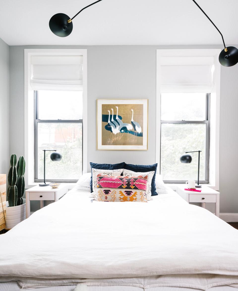 Contemporary bedroom with geometric pillow, arc wall sconce, and symmetrical window placement