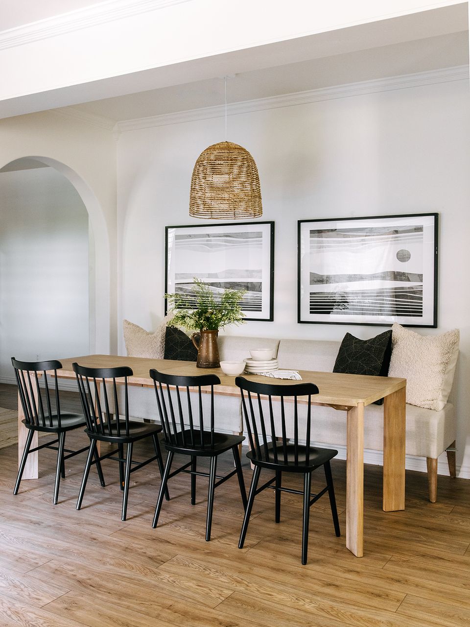 Contemporary dining nook with cream bench, black accents, and woven rattan styling
