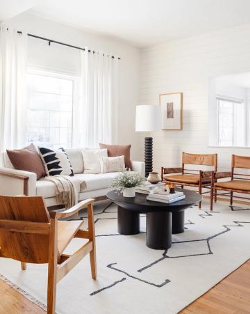 Warm organic modern living room blending mid-century wood chairs, cream sofa, black marble table, and earthy tones