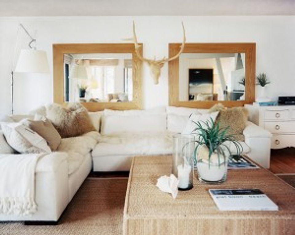 Coastal farmhouse living room with cream sectional, natural wood mirrors, warm neutrals, and relaxed bohemian style.
