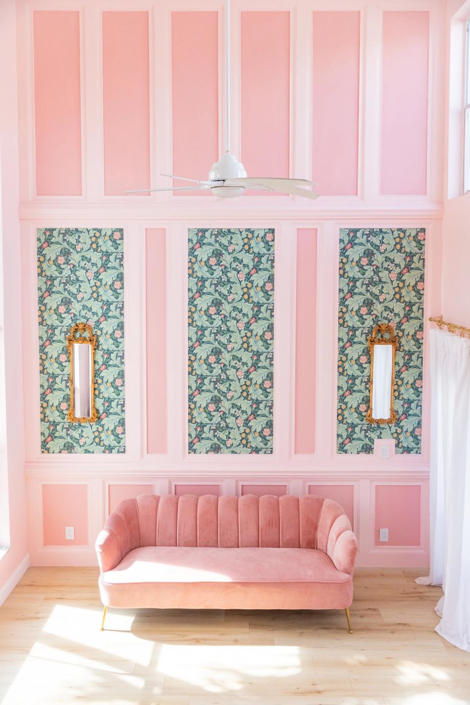 Glamorous blush pink room with botanical paneling, velvet sofa, and art deco mirrors