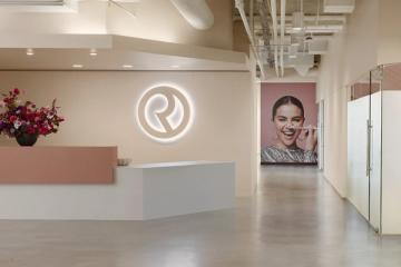 Contemporary reception area with neon logo, split-tone accent wall, and minimalist aesthetic