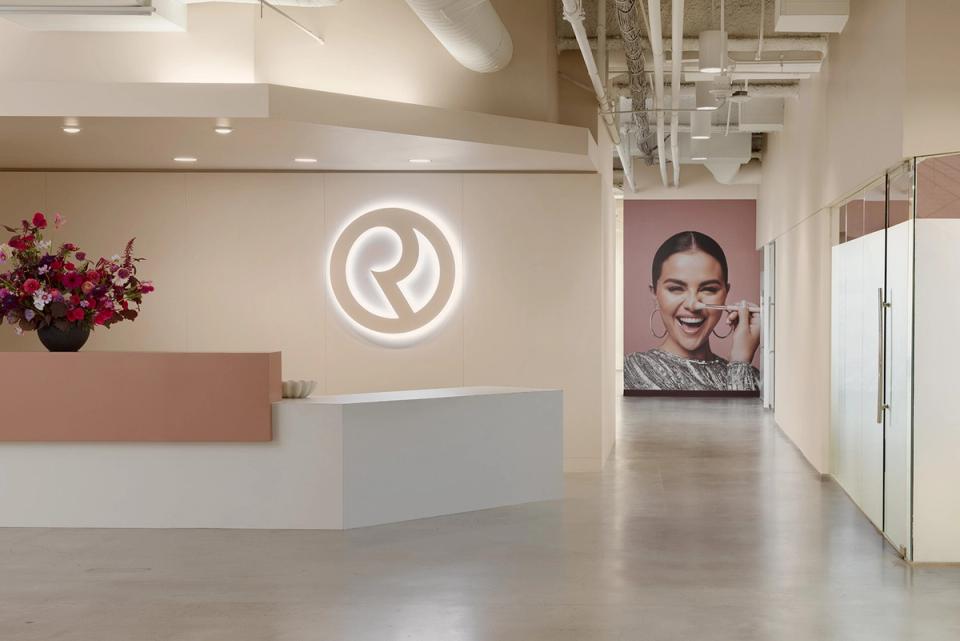 Contemporary reception area with neon logo, split-tone accent wall, and minimalist aesthetic