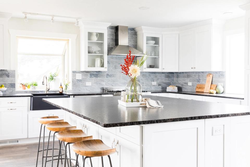 Classic white kitchen with open shelving, gray subway tile backsplash, and light wood bar seating