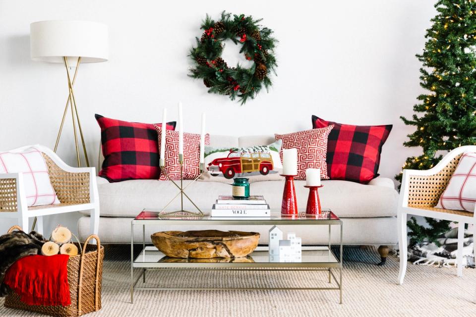 Classic Christmas living room with red buffalo check pillows, cream sofa, natural textures, and festive greenery accents