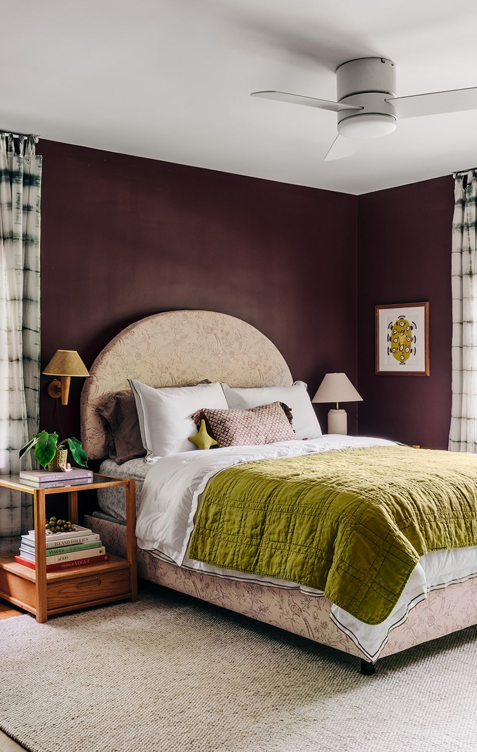 Sophisticated bedroom with deep burgundy walls, rounded upholstered headboard, and chartreuse bedding creating moody elegance.
