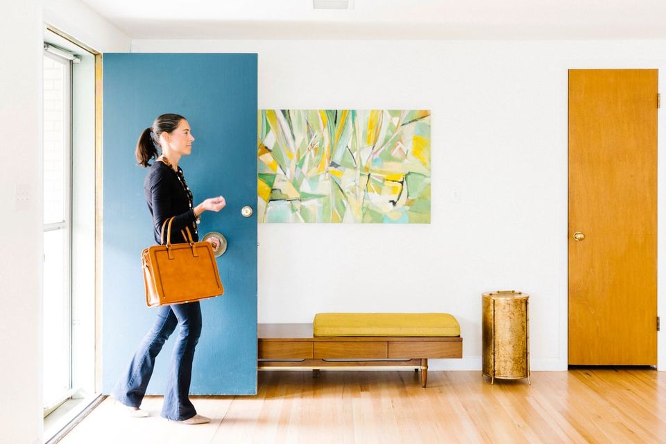 Colorful mid-century entryway featuring blue accent wall, mustard bench, and natural wood tones