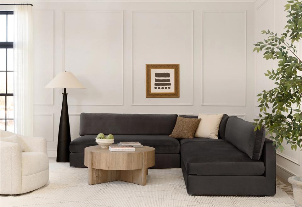 Contemporary living room with charcoal sectional, natural wood table, and calm neutral backdrop