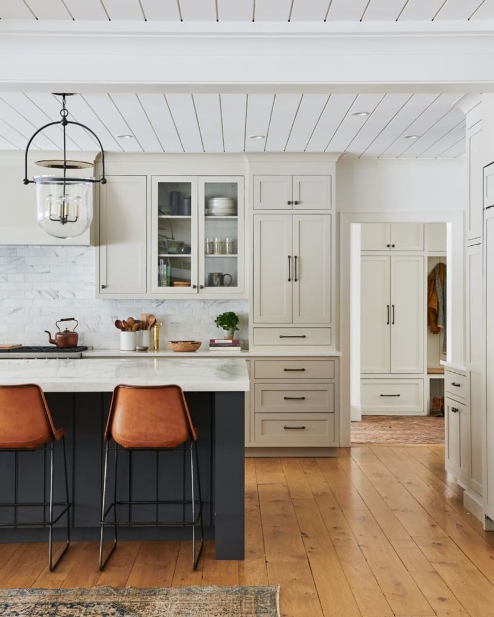 Transitional kitchen blending white cabinetry with dark gray island and warm wood floors, balanced classic-modern aesthetic