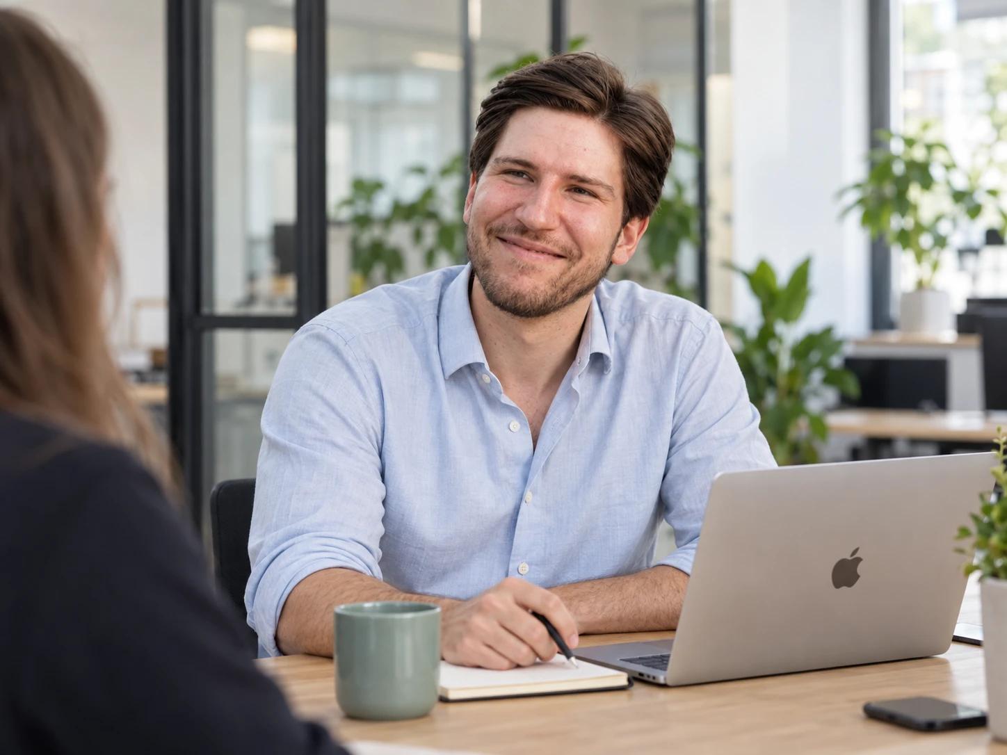 Zwei Personen im Gespräch am Schreibtisch mit Laptop