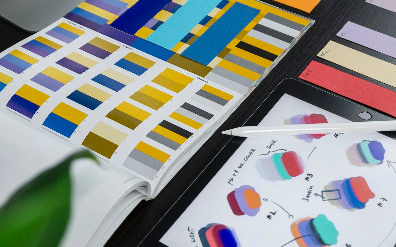 Colour studies and interface sketches arranged beside a tablet and stylus