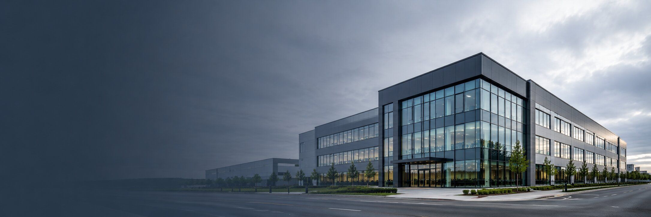 Modern commercial office building viewed from across the street under an overcast sky.