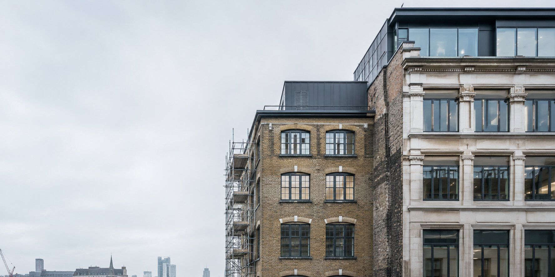 Two adjoining commercial buildings sharing a boundary wall, with scaffolding visible on one property.