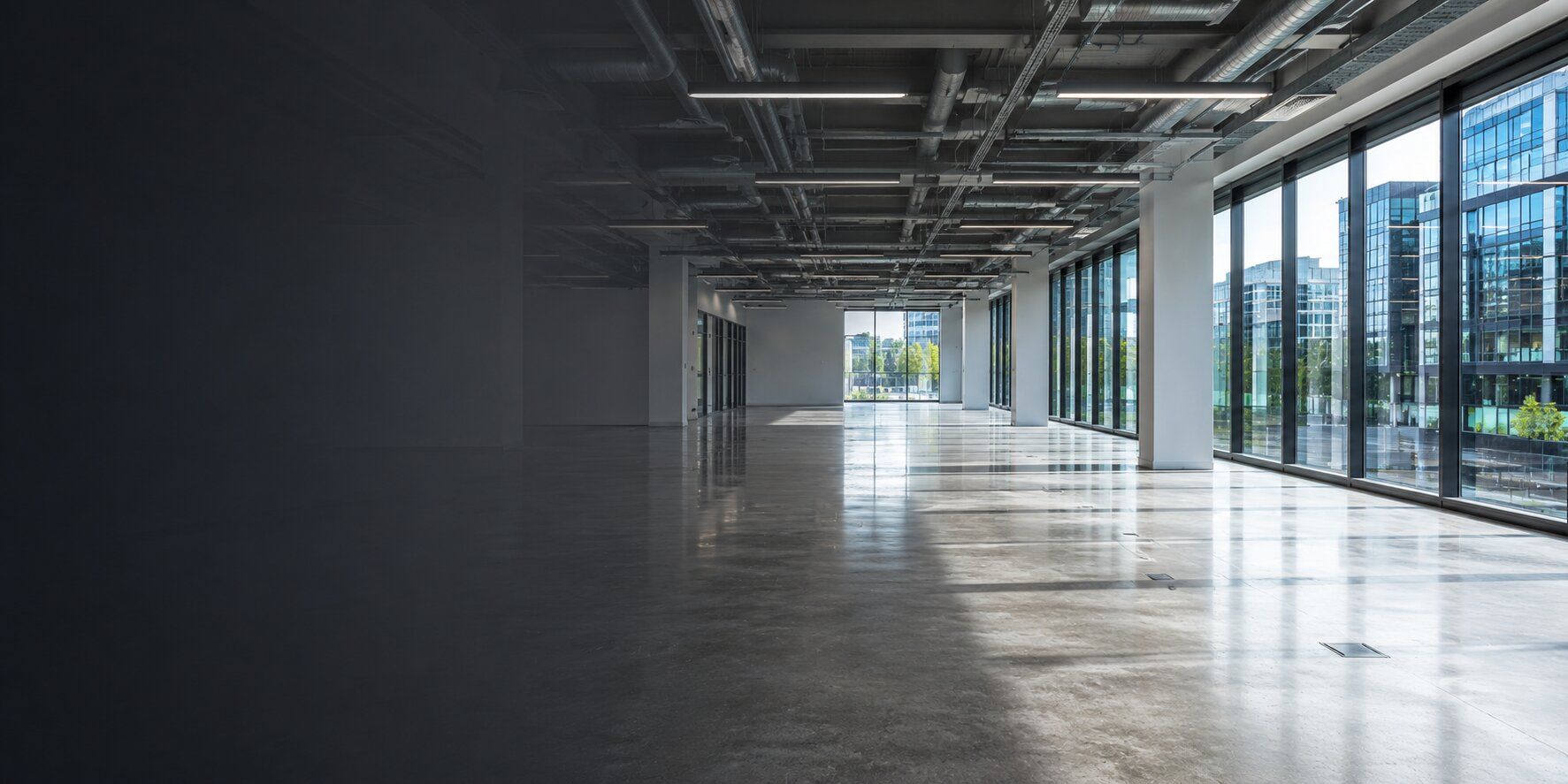 Empty commercial office space with floor-to-ceiling glazing and polished concrete floors.