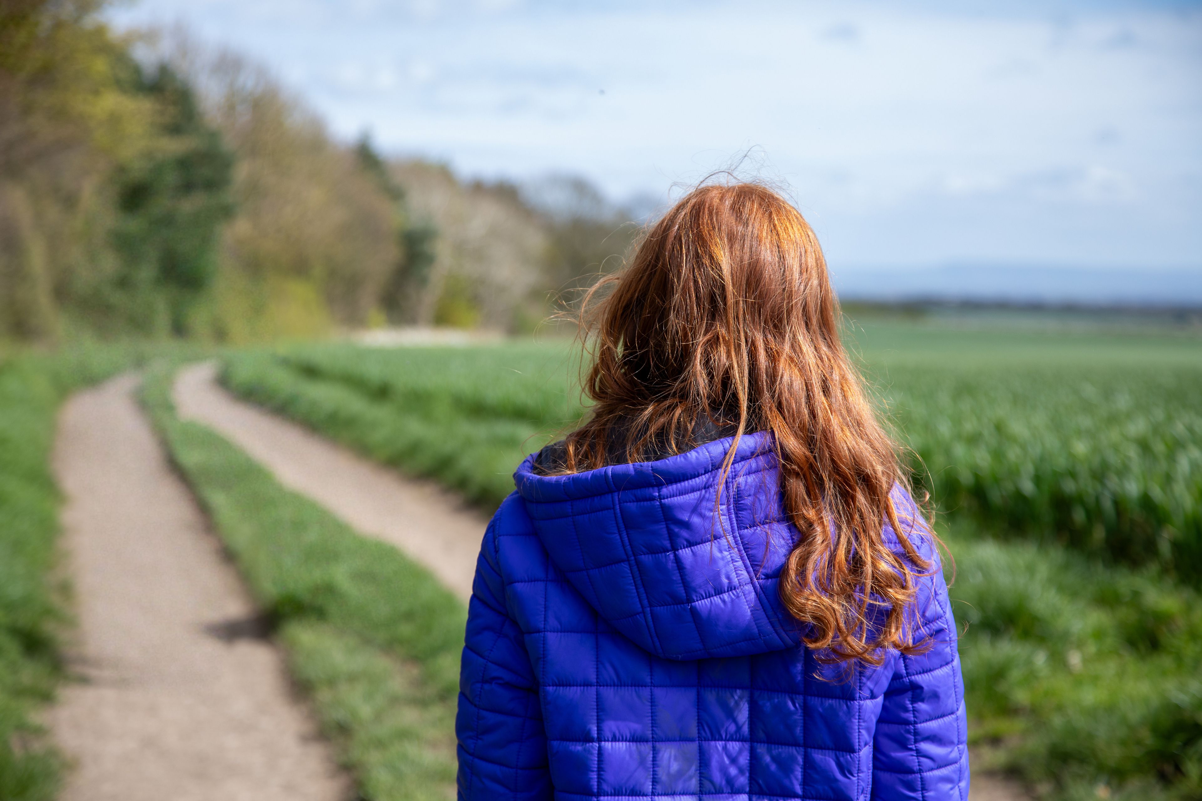 a teenage girl walking down a country lane