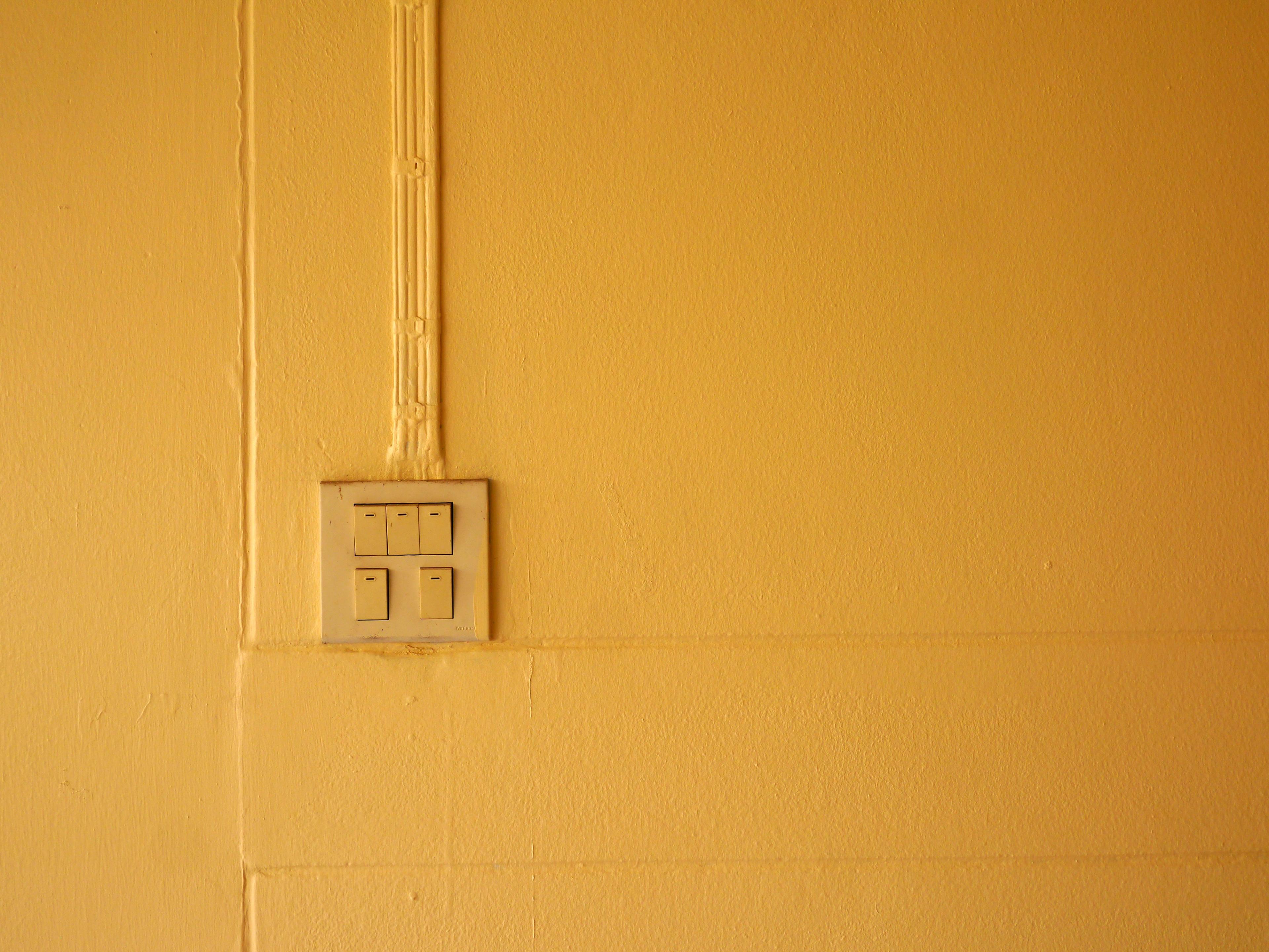 A light switch on a wall where everything is the same colour