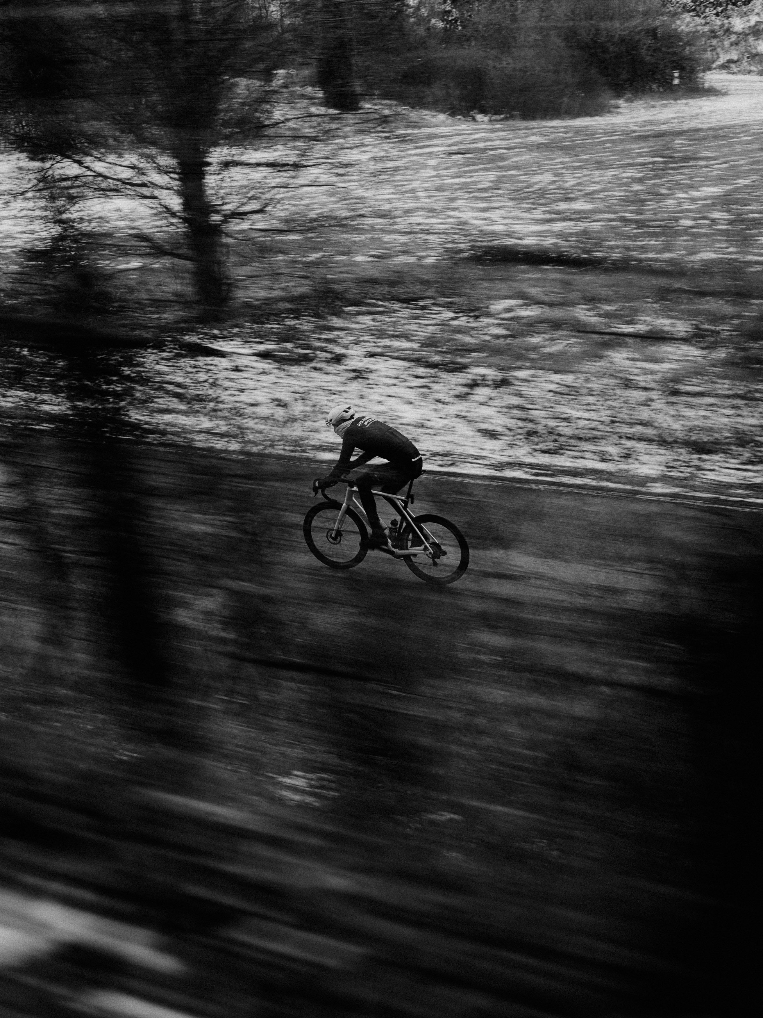 Cyclist in motion blur racing through wooded terrain in black and white
