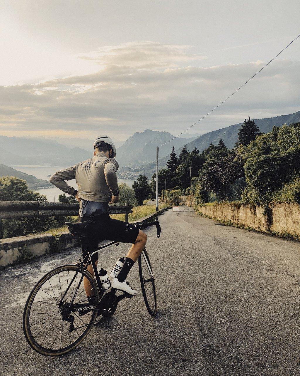 Model wearing grey long sleeve jersey with time trial bike on mountain road overlooking valley