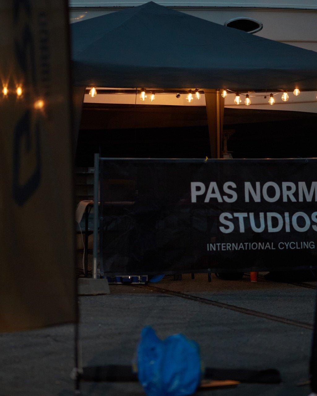 Evening view of outdoor event tent with string lights and brand signage