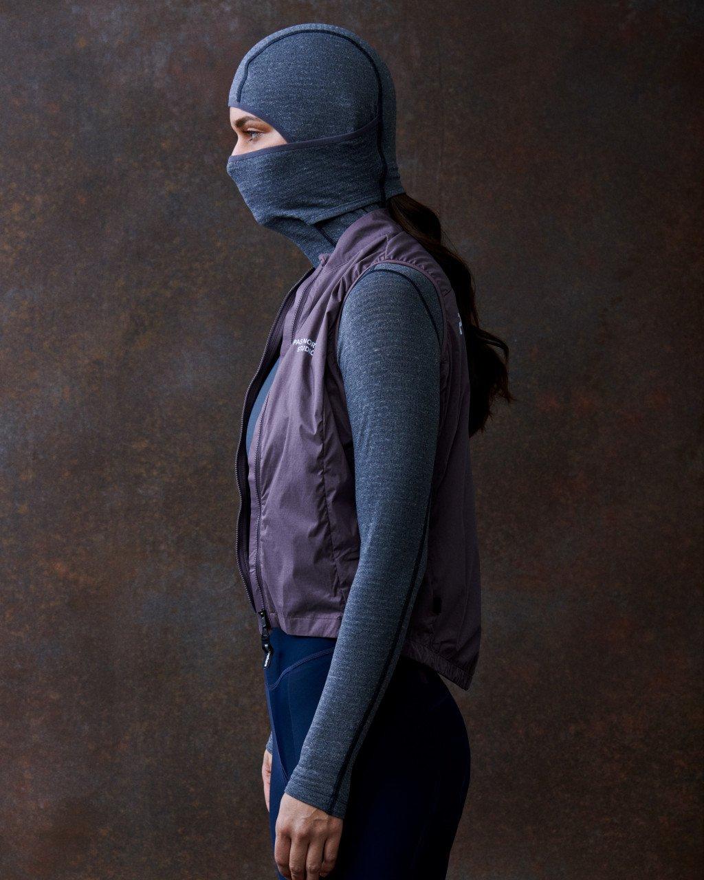 Model wearing grey base layer, purple vest, blue tights, and grey balaclava in studio shot