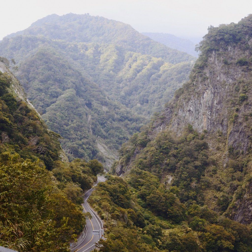 Winding mountain road through forested valley with steep canyon walls