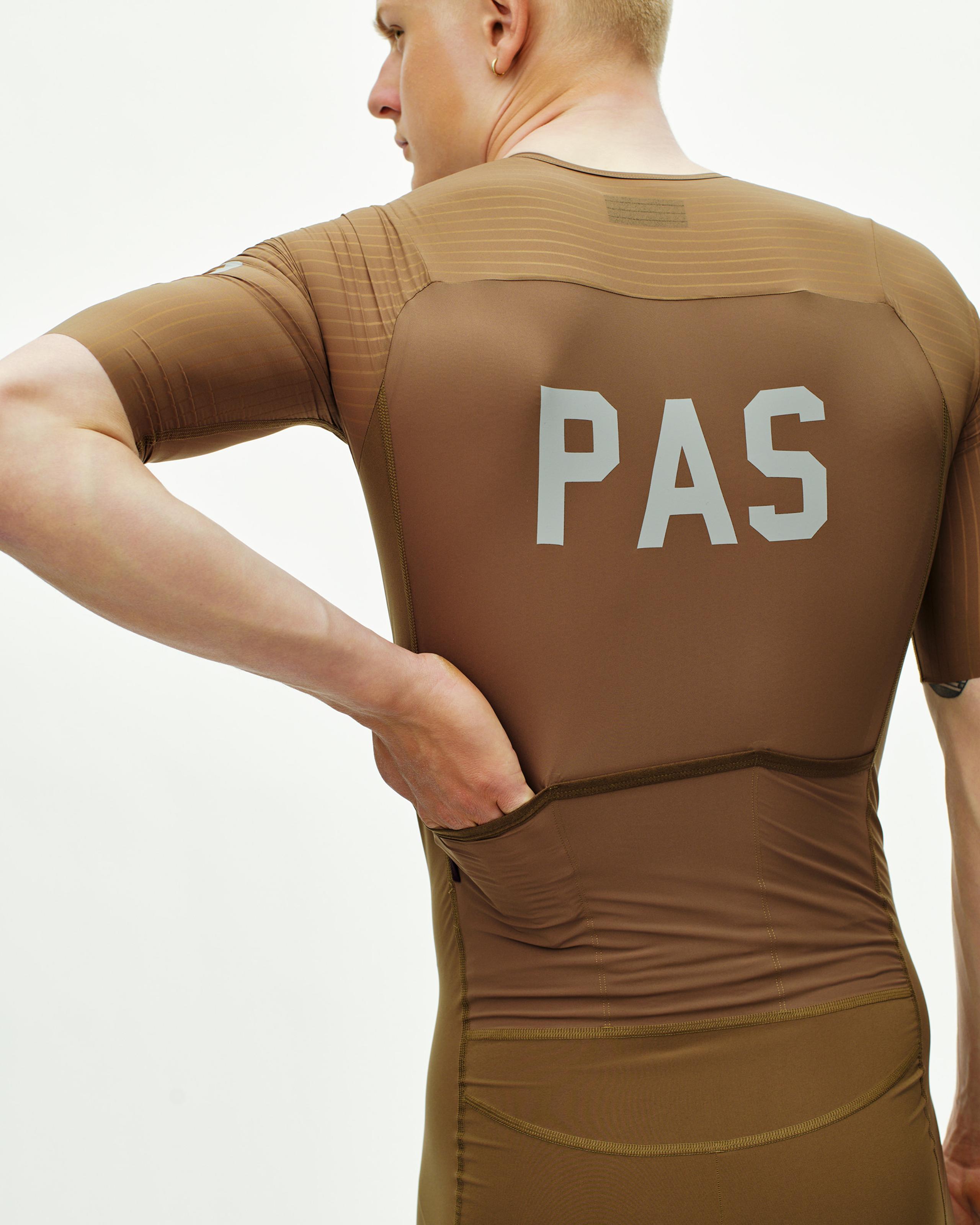 Brown PAS Mechanism Pro speedsuit on model, rear view with white chest logo