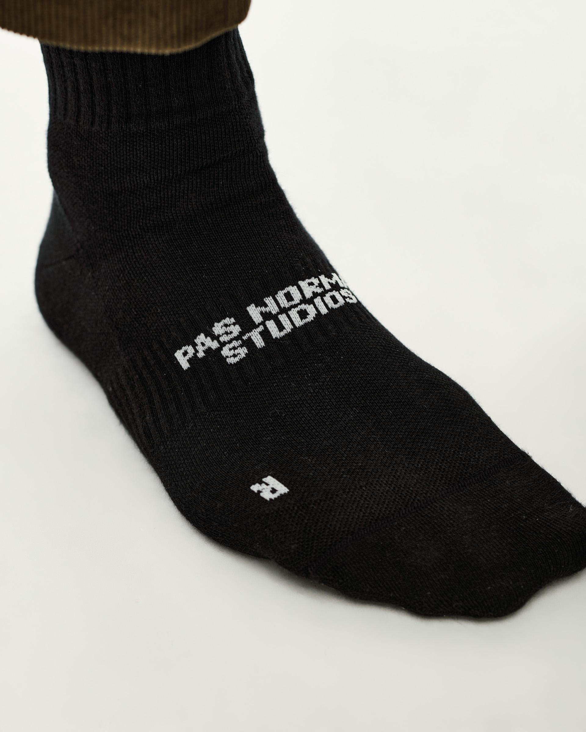 Black Off-Race sock, side detail view on model with white knitted logo on foot