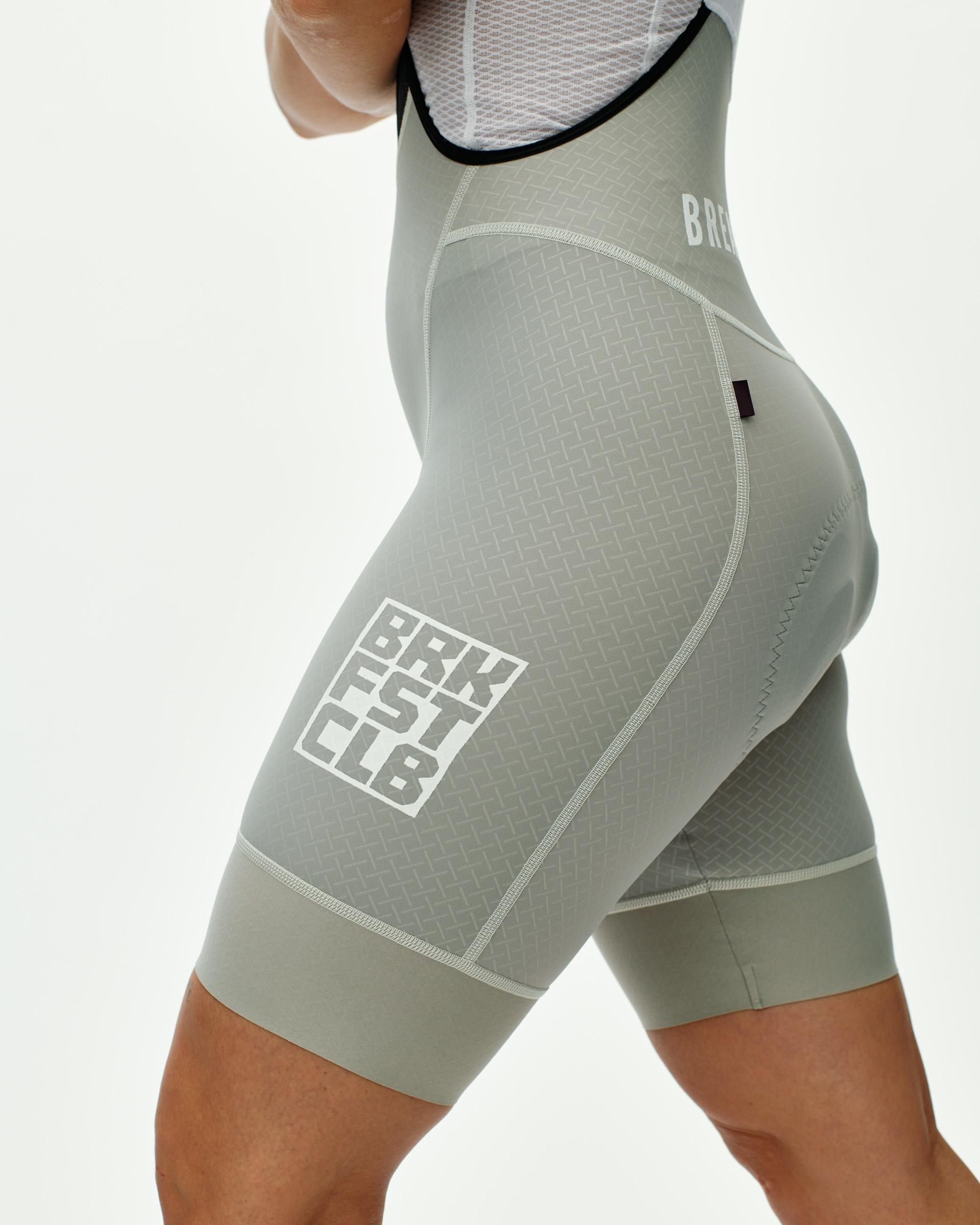 Light Grey Mechanism cycling bibs on model, side view with white Breakfast Club logo print on thigh