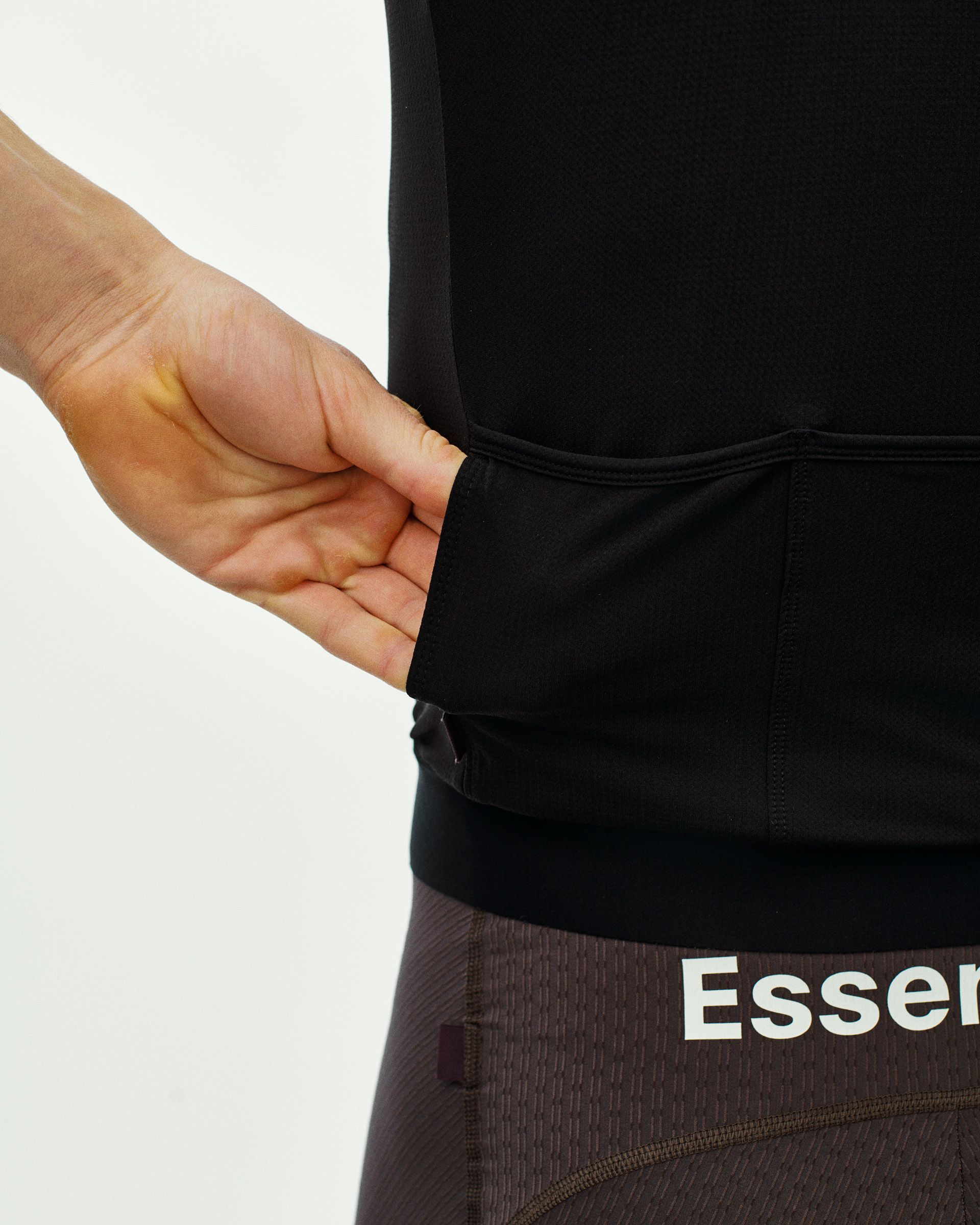 Black Essential cycling jersey on model showing elastic waistband and ribbed sleeve cuff