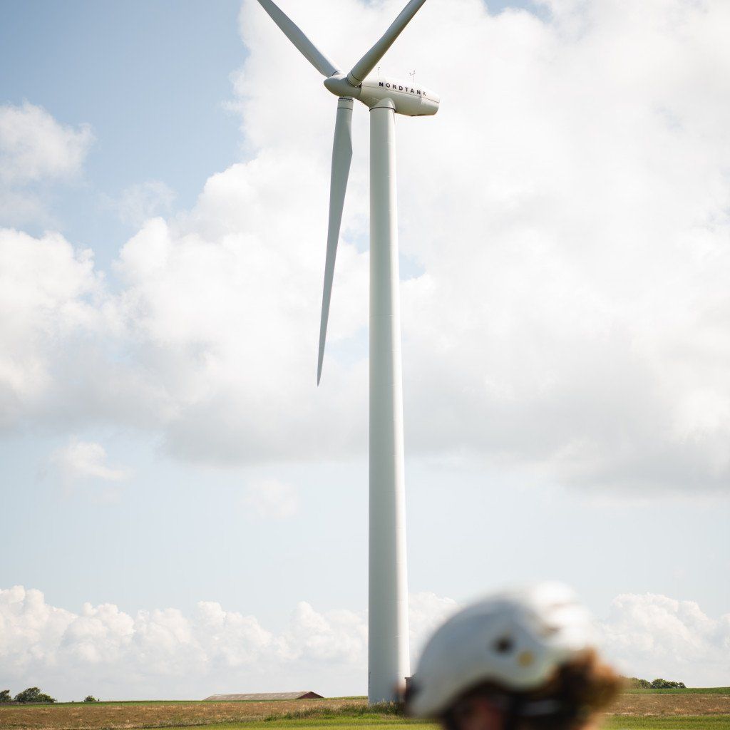 Wind turbine in countryside with blurred cyclist helmet in foreground