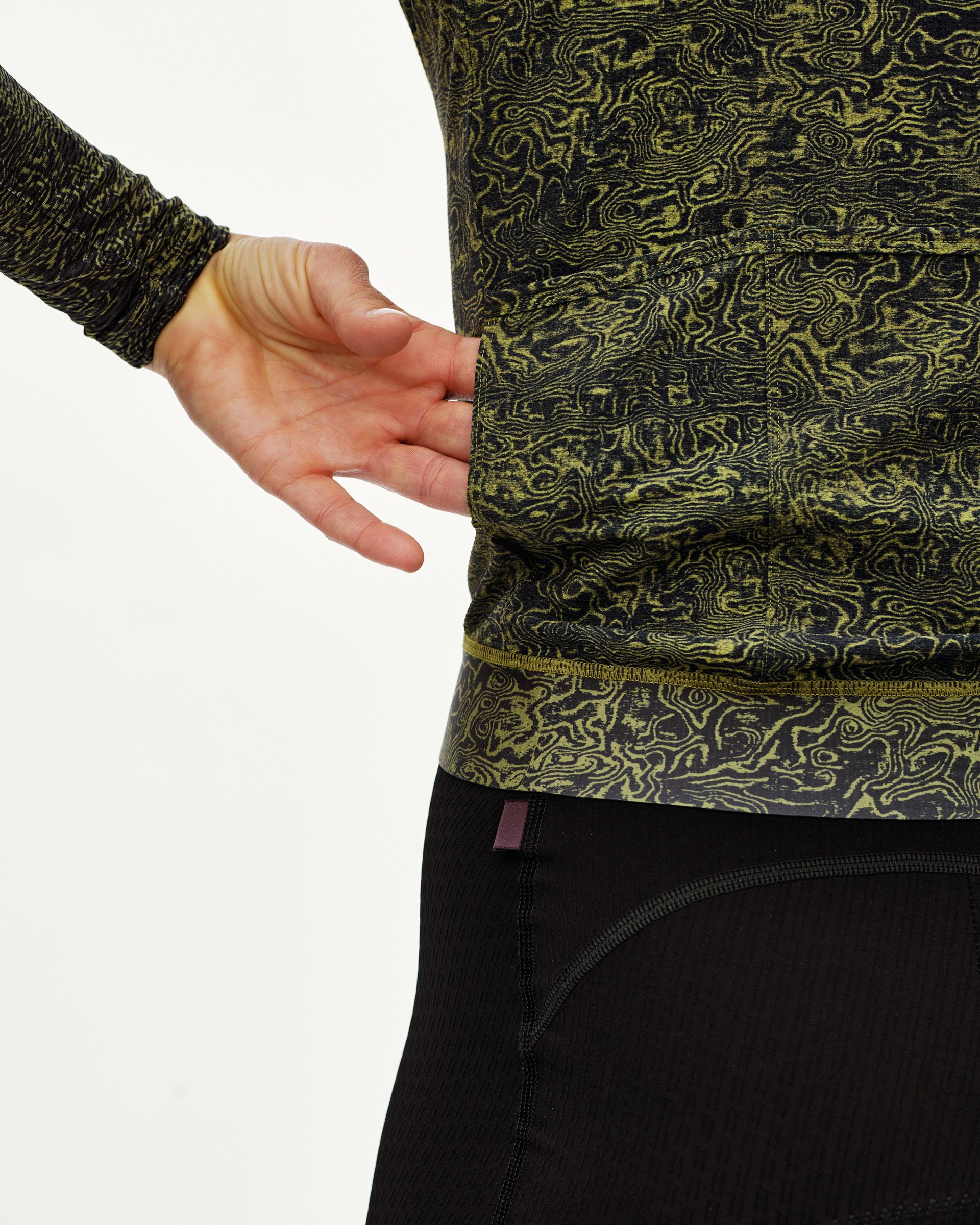 Dark Lime Essential long sleeve cycling jersey, side detail on model showing hem and all-over grain print
