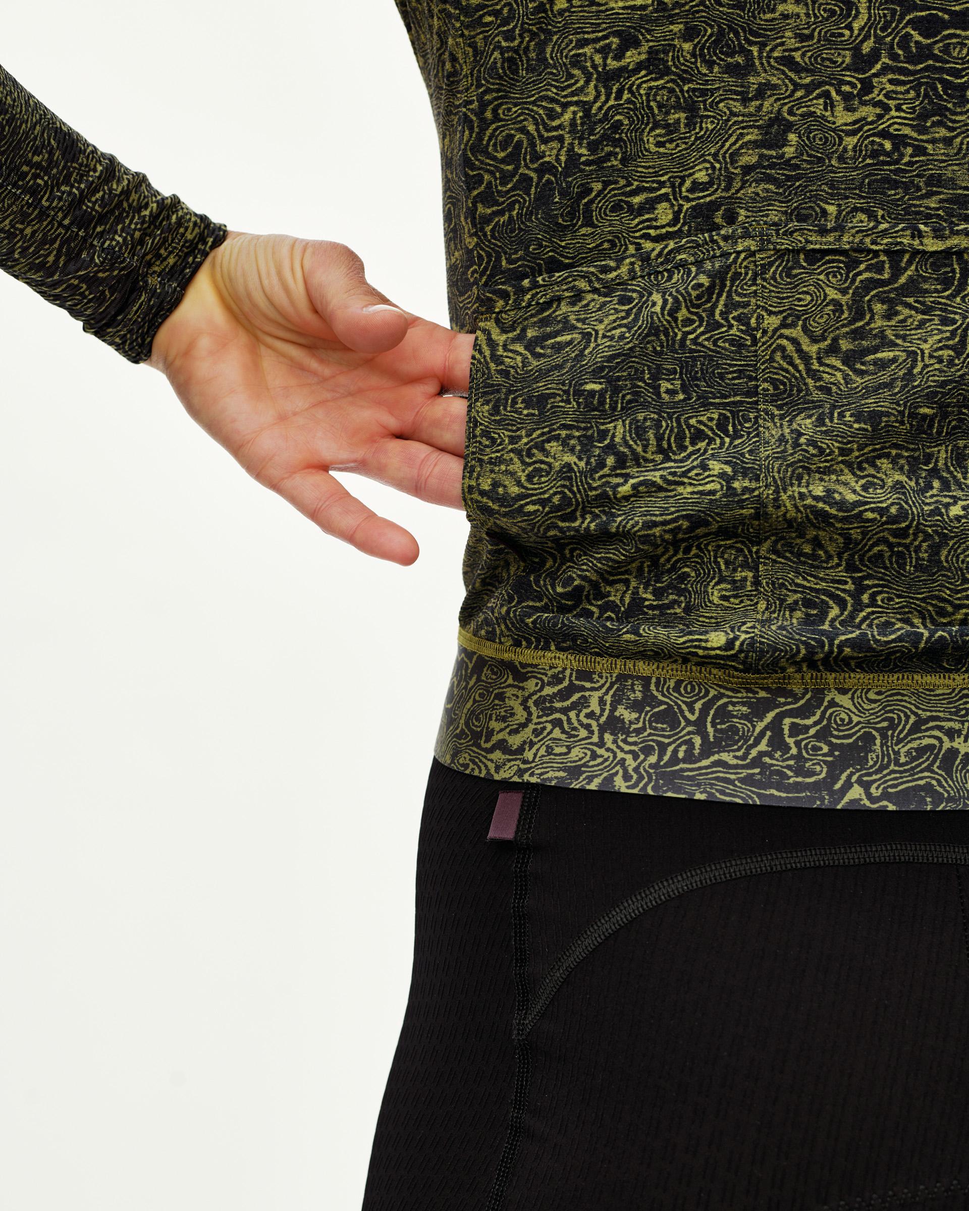 Dark Lime Essential long sleeve cycling jersey, side detail on model showing hem and all-over grain print