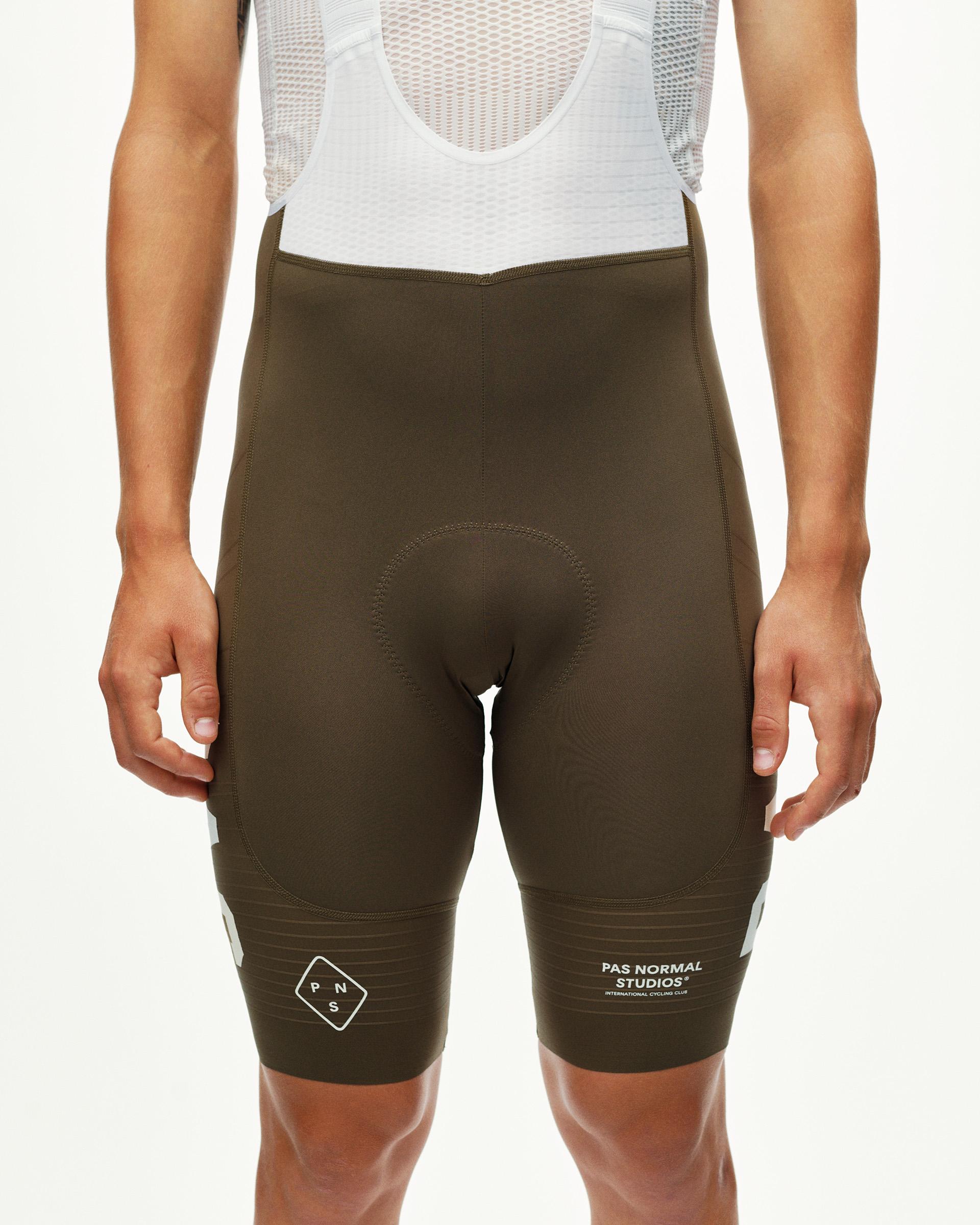 Dark Earth khaki PAS Mechanism Pro men's cycling bibs, front view on model with white leg print