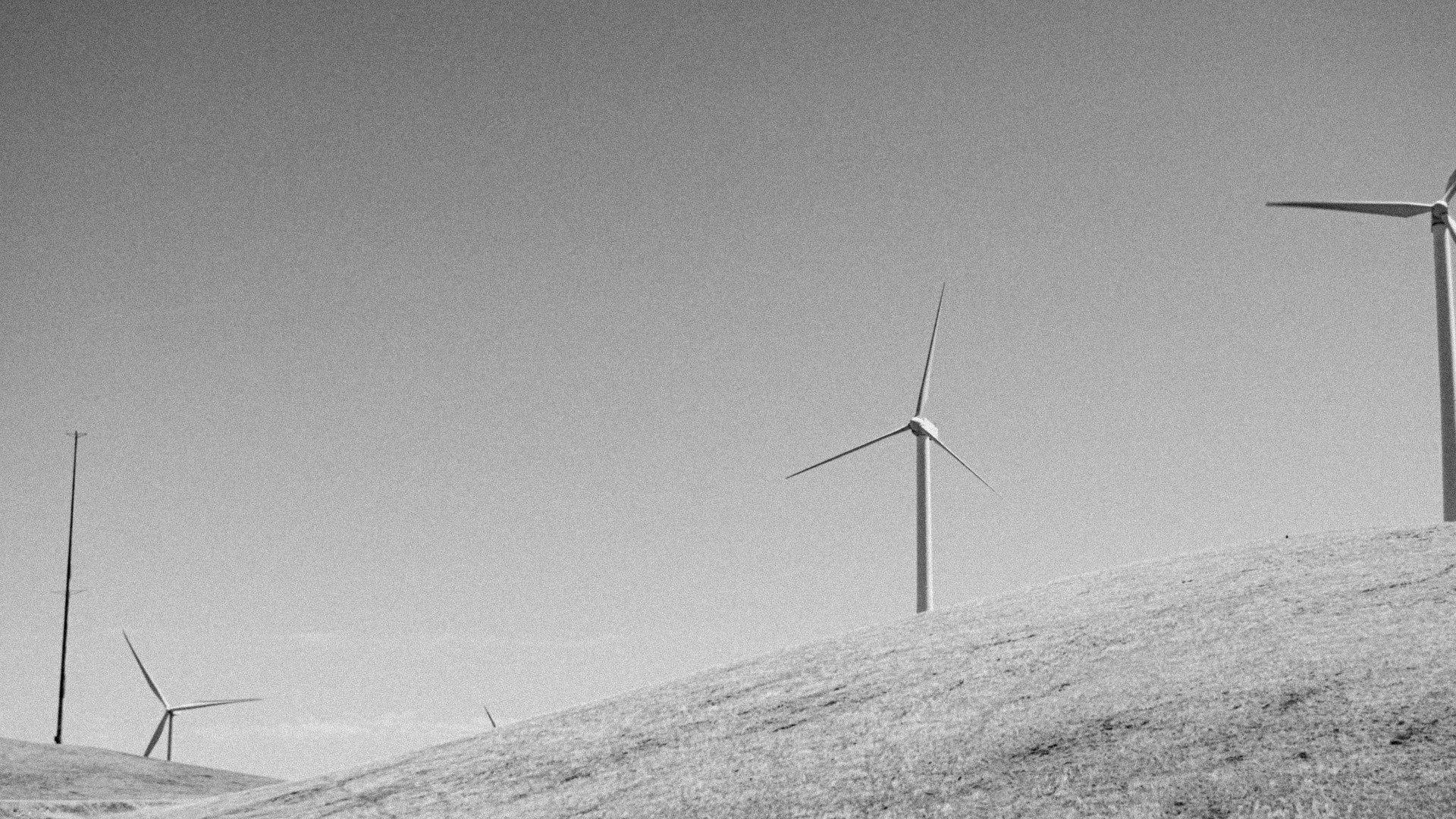 Black and white landscape with wind turbines on rolling hills