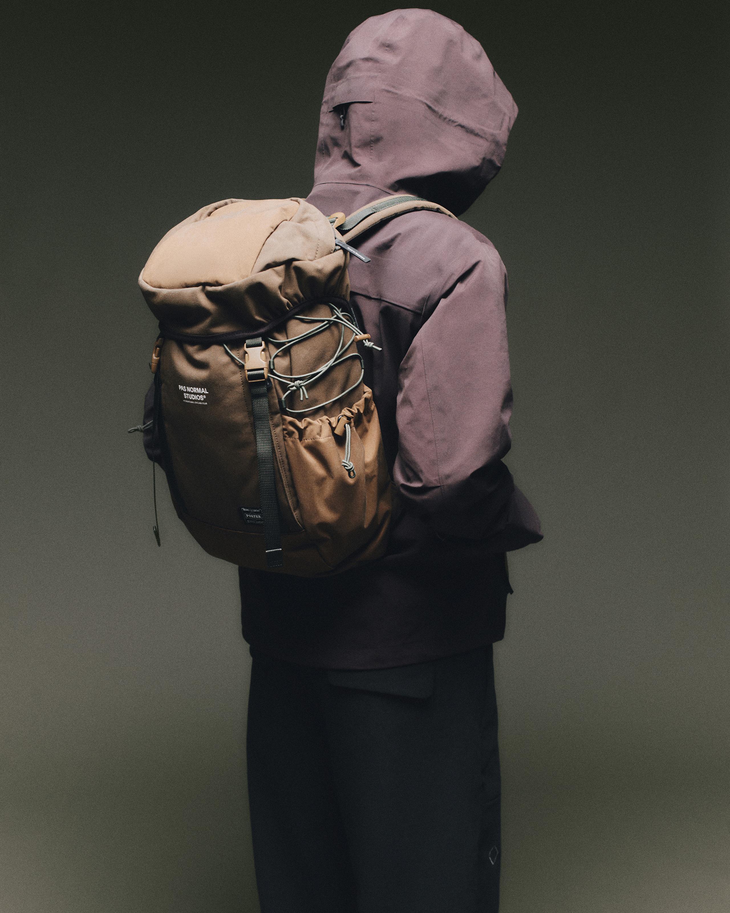 Light Brown Porter-Yoshida backpack worn on model, rear view with roll-top closure and cord bungee front panel