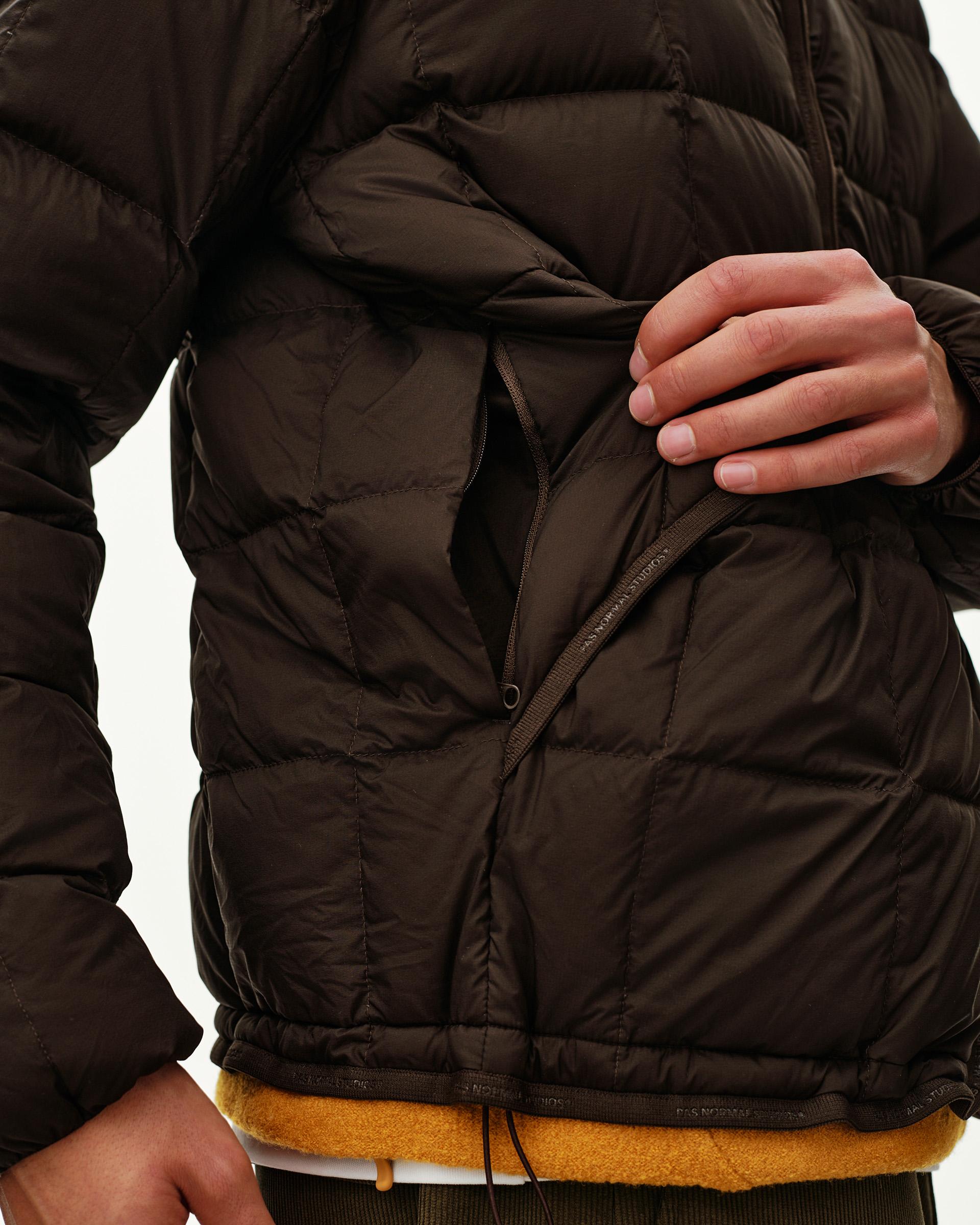 Dark Coffee Off-Race Down Liner jacket, detail view on model showing open zip chest pocket with quilted paneling