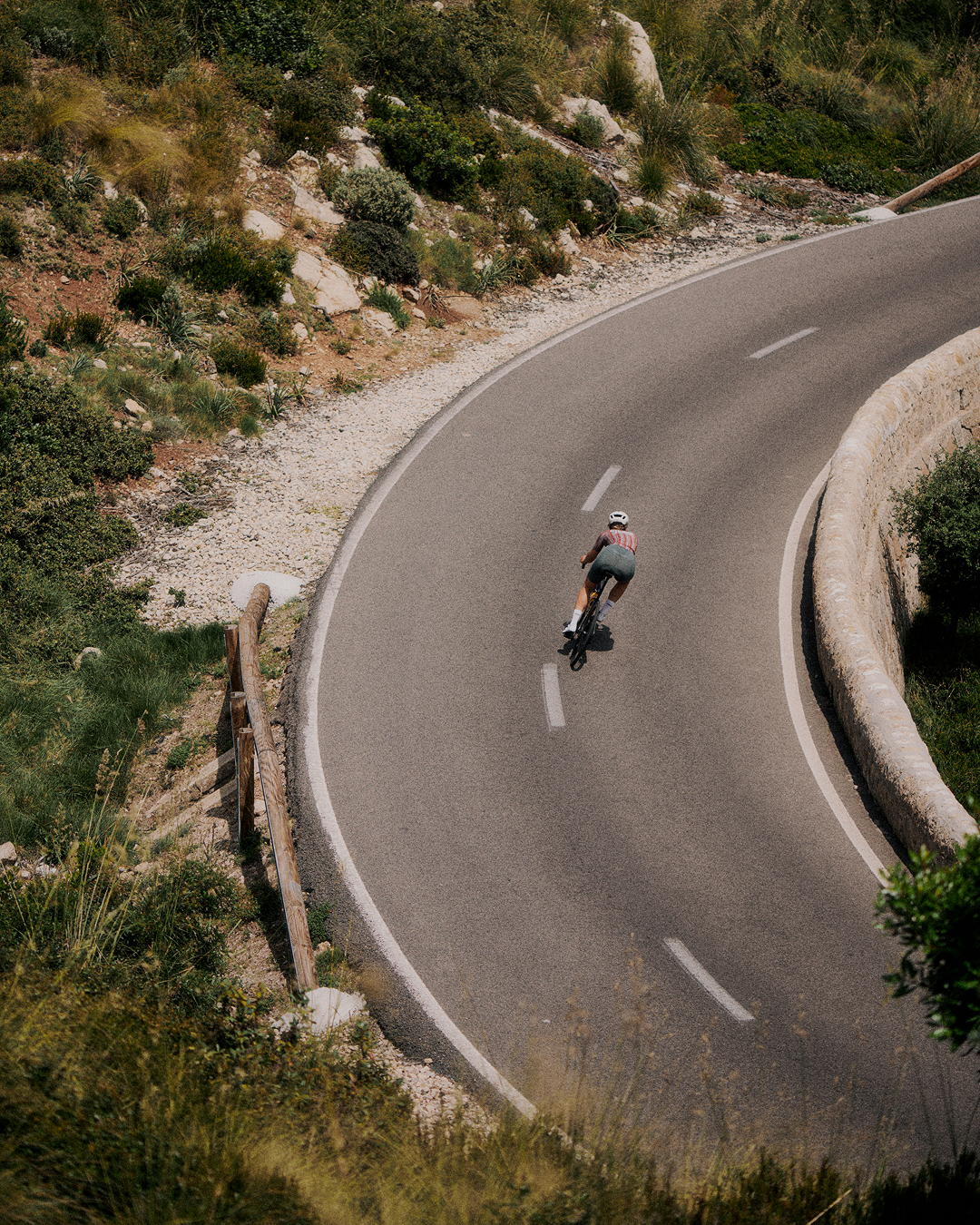 Cyclist in striped jersey riding through winding mountain road curve
