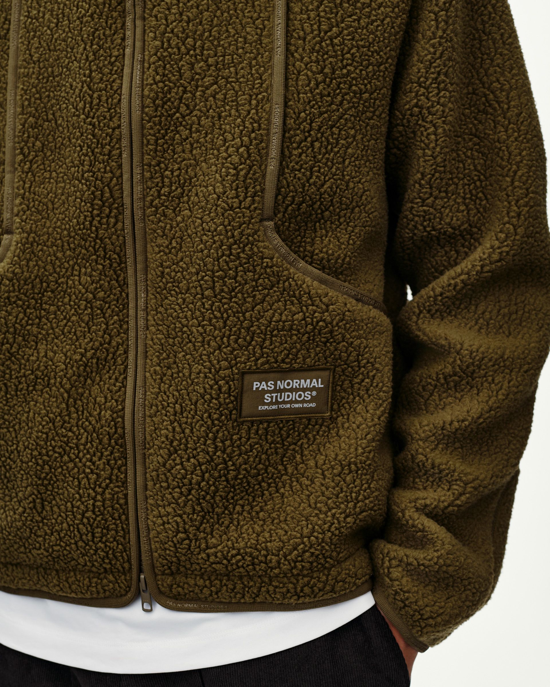 Deep Olive Off-Race Pile Fleece jacket, front detail on model with sherpa texture and branded rubber patch