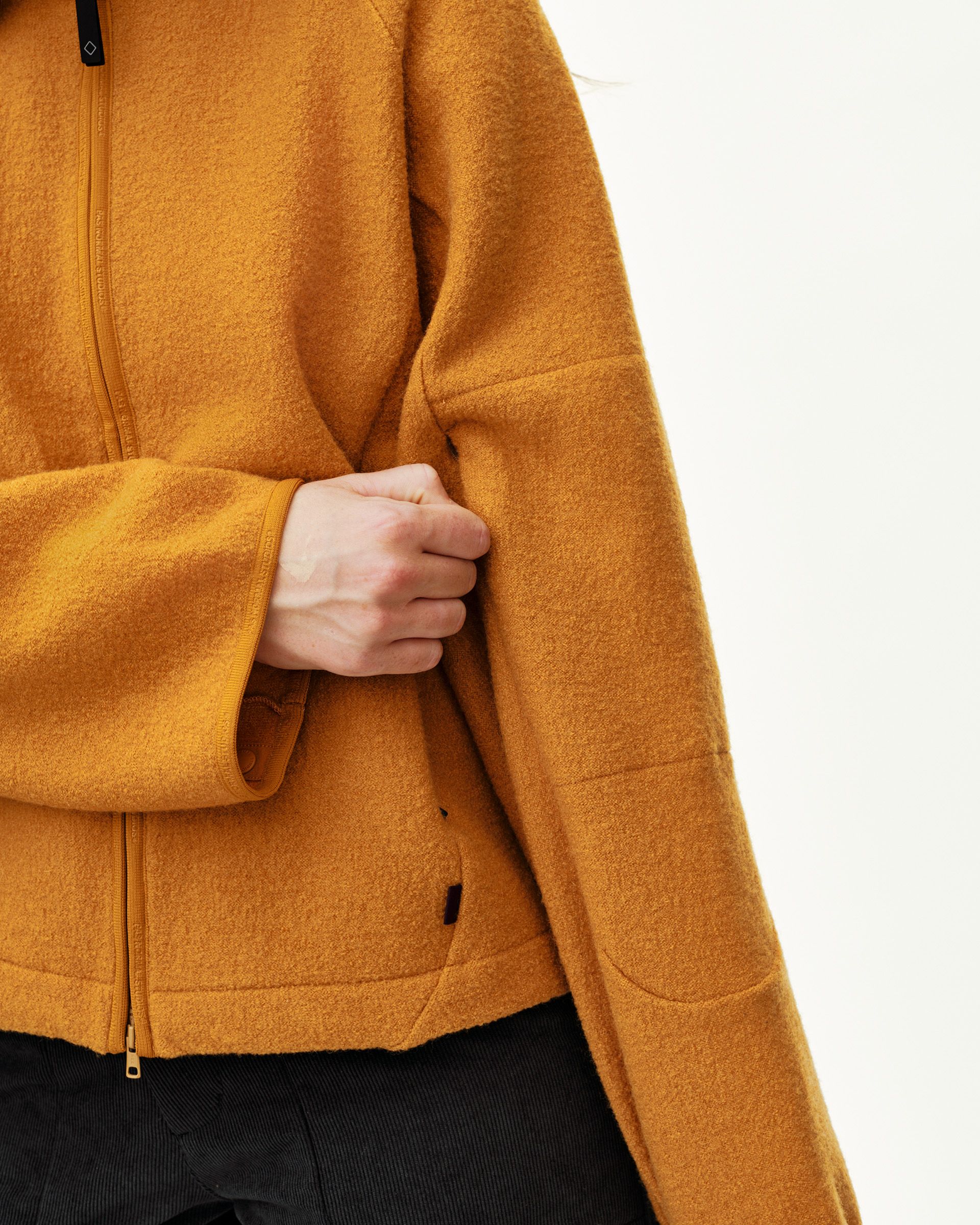 Ochre Off-Race Boiled Wool jacket, detail view on model showing front zip and hand pocket
