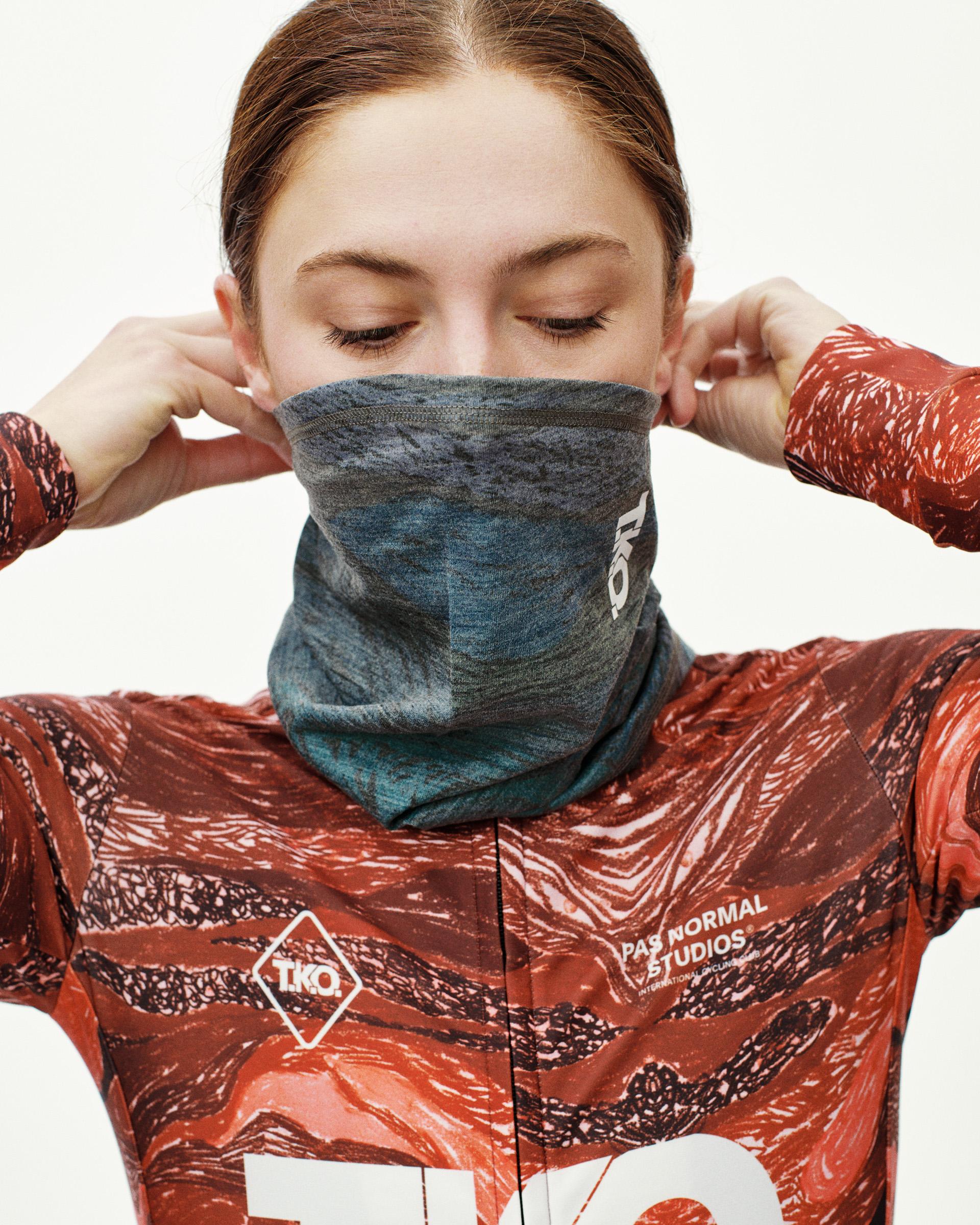 Dark Multi T.K.O. Merino necktube on model, front view pulled up over face with marbled blue-grey print