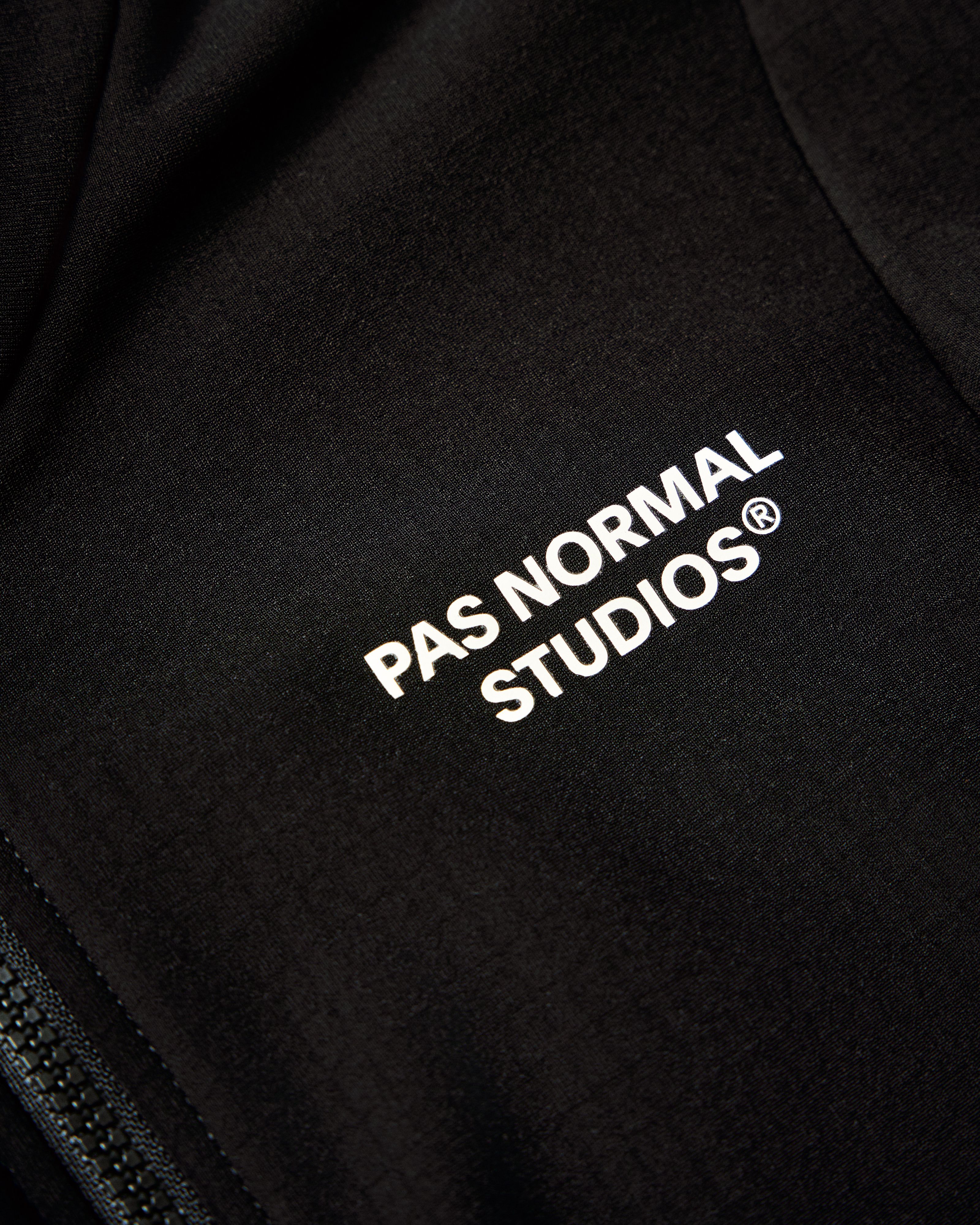 Black fleece-backed fabric with white logo branding, showing soft grid texture for warmth and comfort