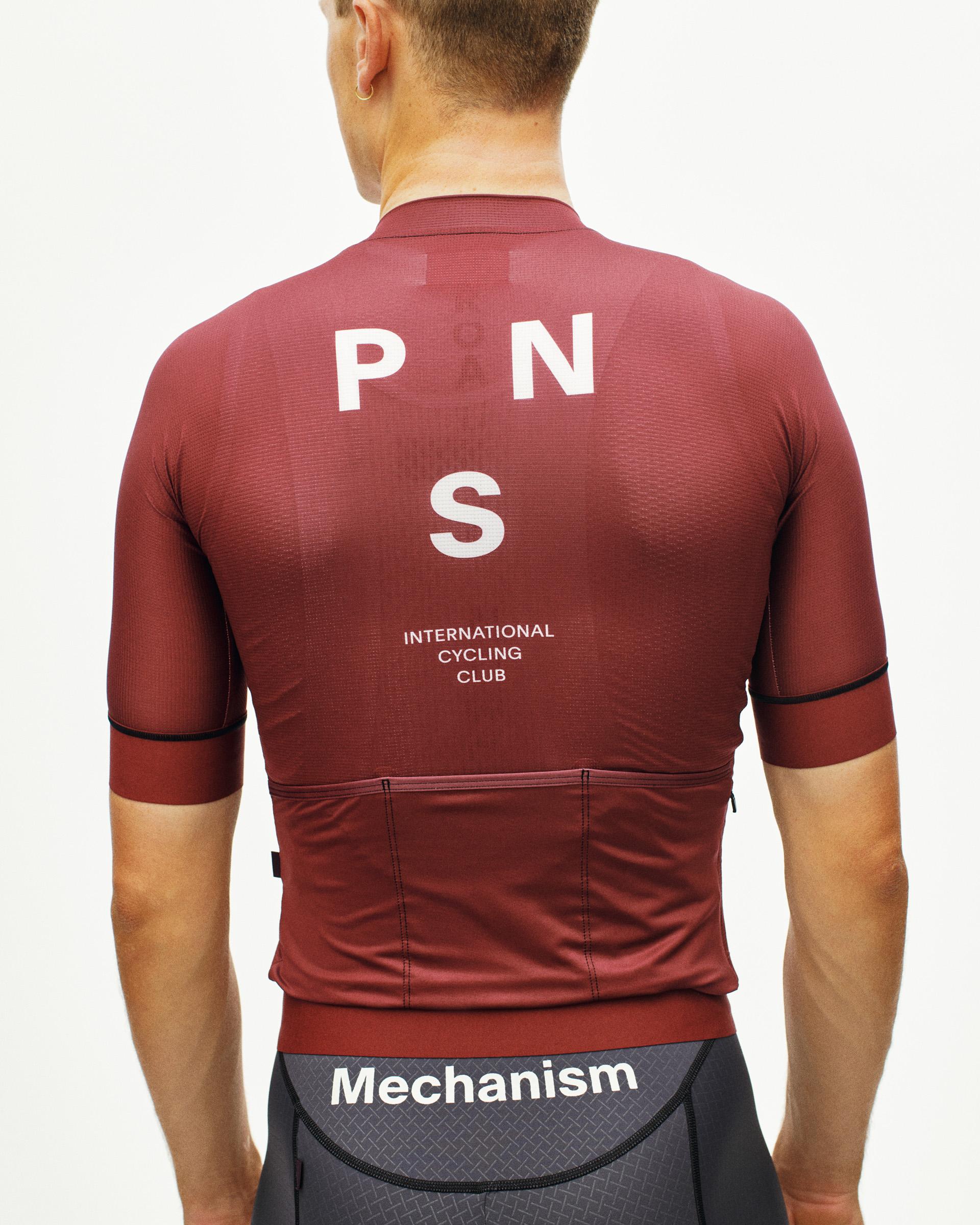 Maroon Mechanism cycling jersey on model, rear view with white PNS International Cycling Club print