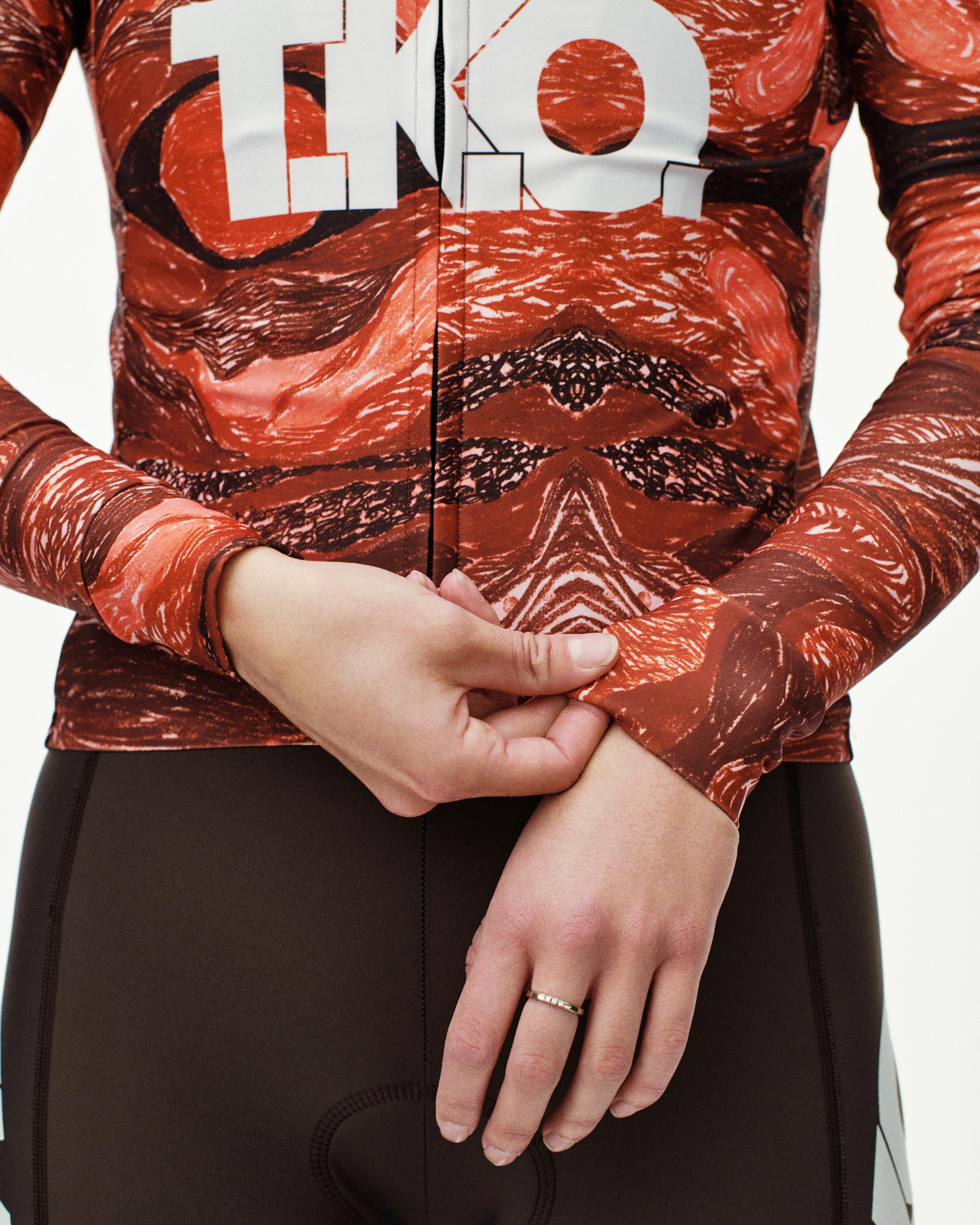 Red T.K.O. Mechanism long sleeve cycling jersey, front detail on model with all-over red terrain print and white chest logo