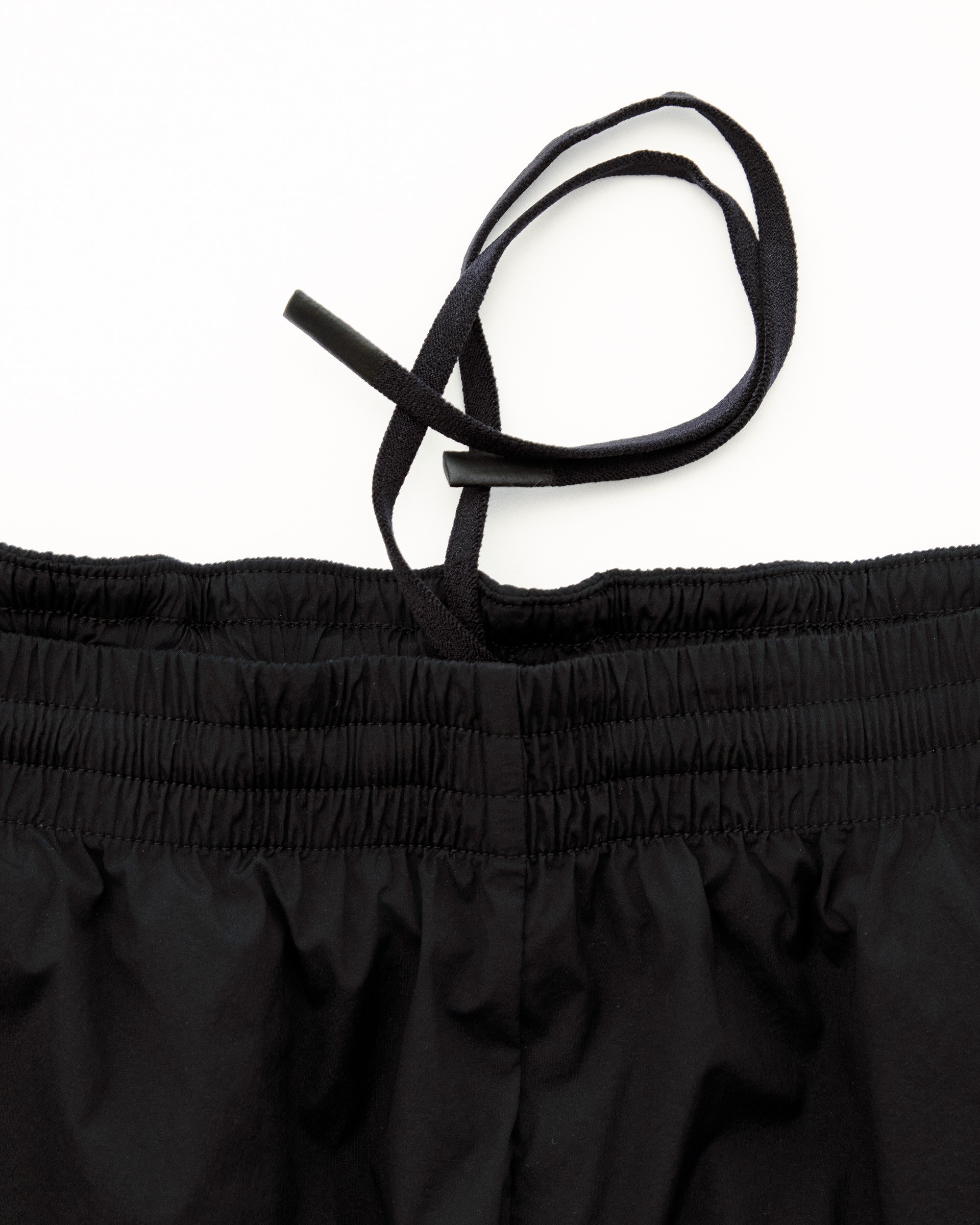Black drawcord threaded through elastic waistband with cord lock for adjustable fit