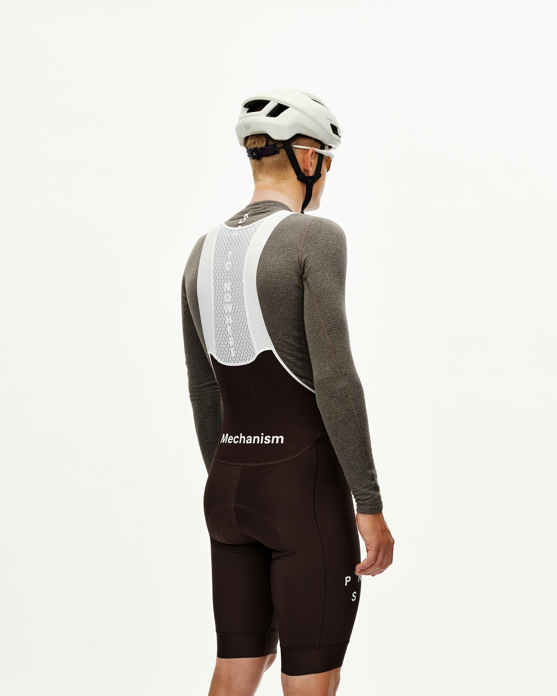 Dark Coffee Mechanism Thermal cycling bibs on model, rear view with white mesh bib straps and Mechanism wordmark