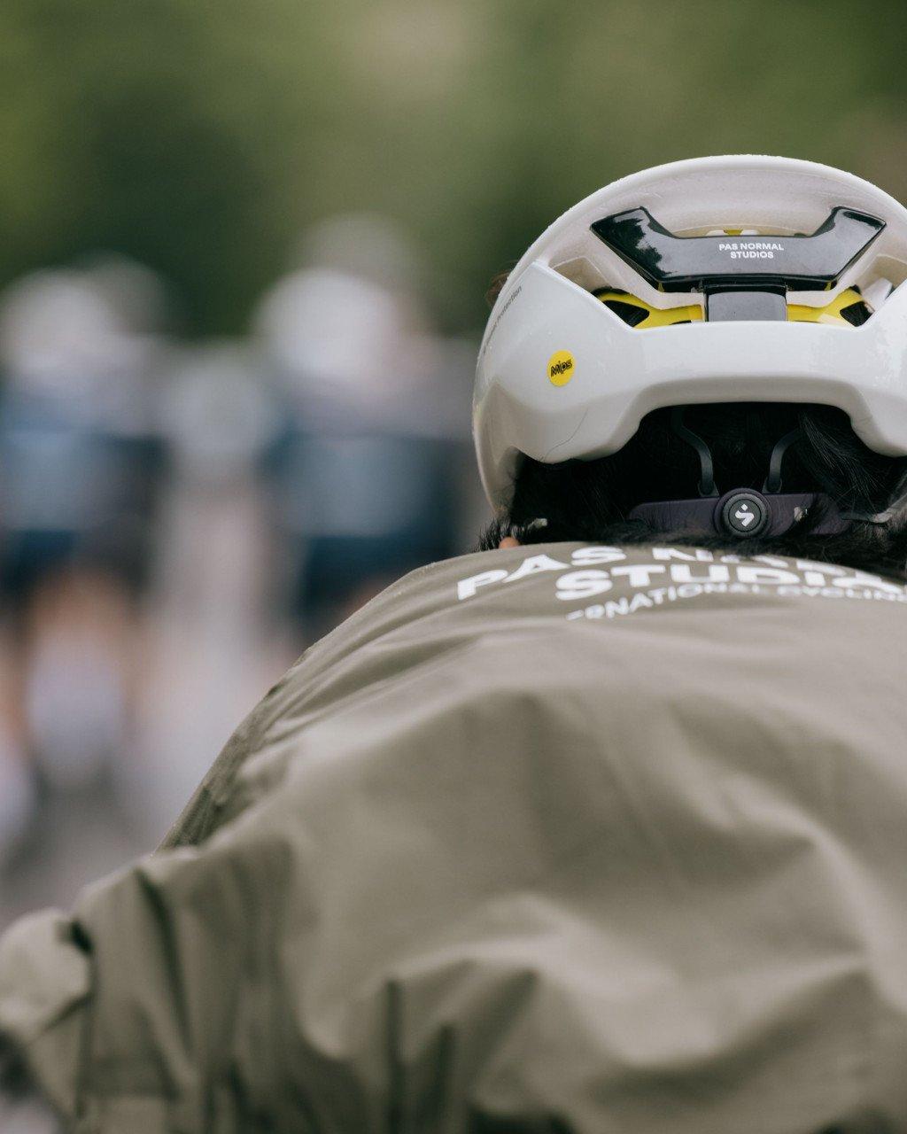 Model wearing white cycling helmet with yellow accents and beige jersey with white lettering
