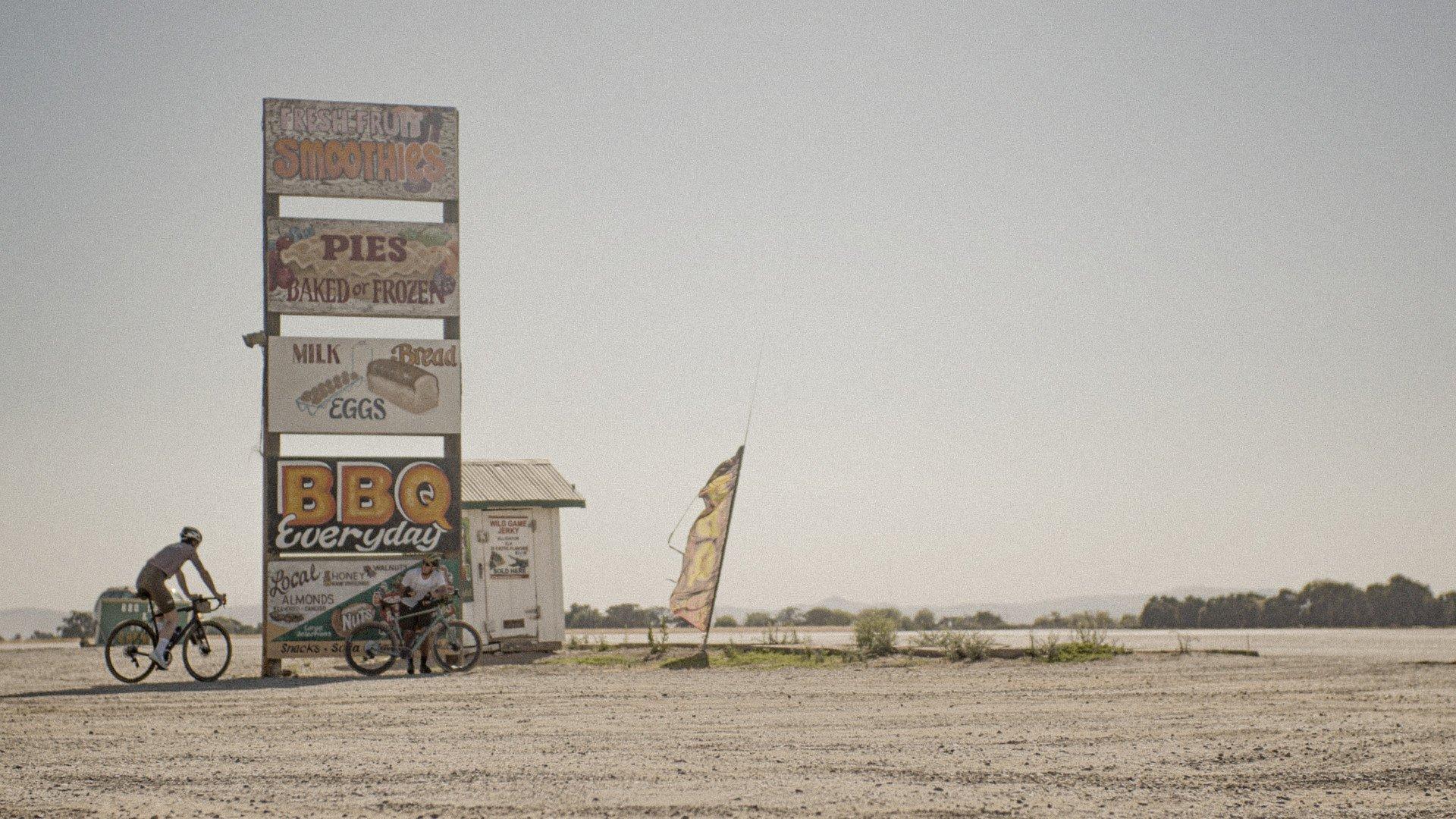 Cyclist beside vintage roadside signs in desert landscape