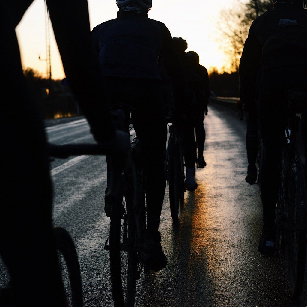 Cyclists silhouetted against sunset light on road