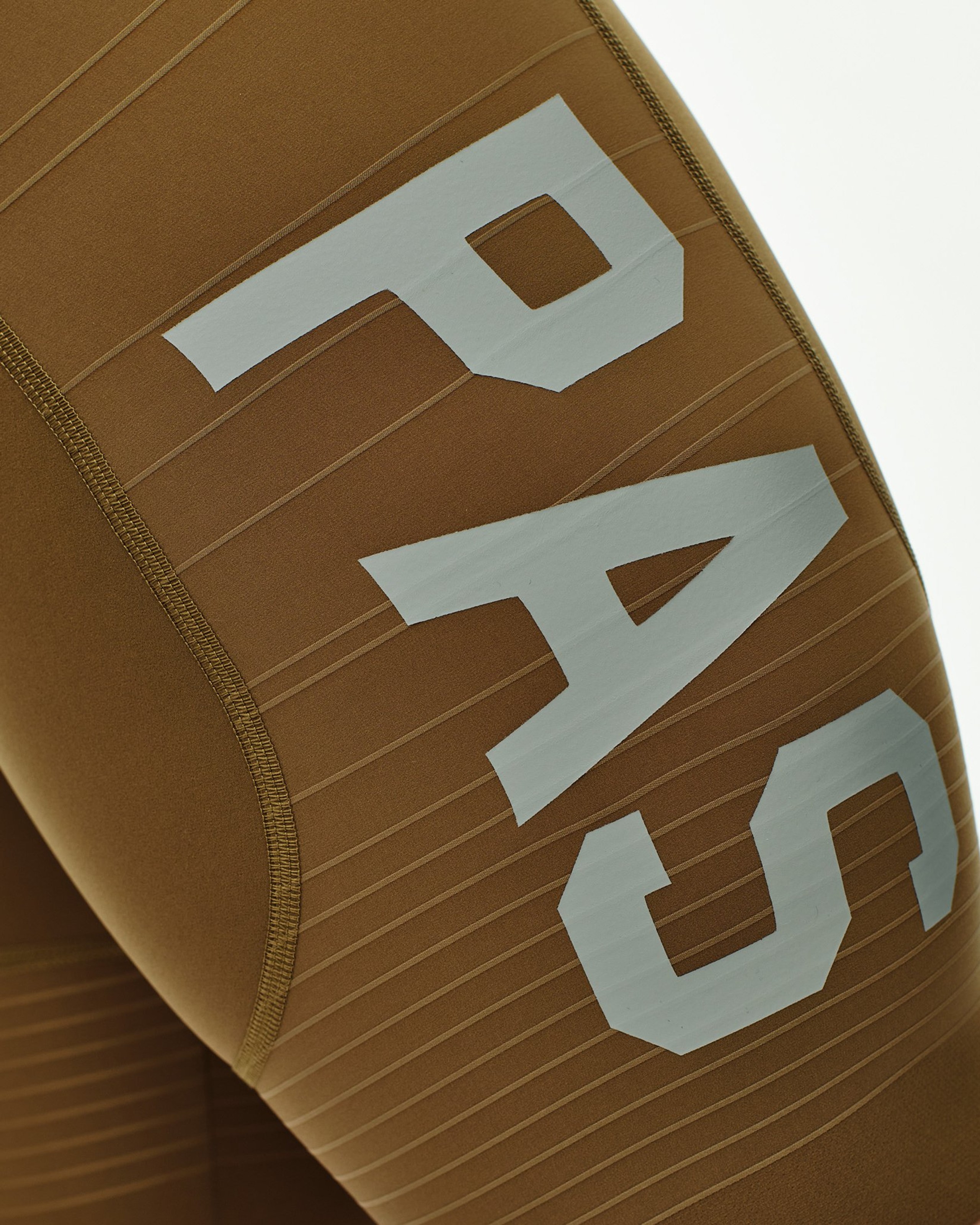 Brown PAS Mechanism Pro speedsuit detail view with white PAS lettering on ribbed fabric panel